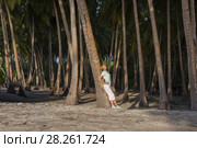 Young beautiful woman standing in a tropical forest leaning on a palm tree. Стоковое фото, фотограф Некрасов Андрей / Фотобанк Лори