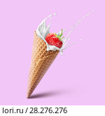 Ice cream waffle cone with milk splash and strawberry isolated on pink. Стоковое фото, фотограф Ярослав Данильченко / Фотобанк Лори