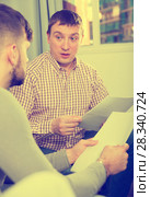 Troubled man discussing documents with partner on couch. Стоковое фото, фотограф Яков Филимонов / Фотобанк Лори