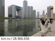 TIANJIN, CHINA - APRIL 8, 2017. A modern building along the Haihe River and fishermen in Tianjin, China. Редакционное фото, фотограф Яна Королёва / Фотобанк Лори