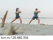 Fitness, sport, friendship and lifestyle concept - smiling couple making stretching yoga exercises on beach at morning. Стоковое фото, фотограф Kirill Kedrinskiy / Ingram Publishing / Фотобанк Лори