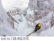 Climber abseiling back down using a double rope during an extreme winter climbing. Dolomiti (East Alps), Trentino, Italy, Europe. Стоковое фото, агентство Ingram Publishing / Фотобанк Лори
