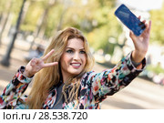 Portrait of a beautiful young woman selfie in the park with a smartphone. Стоковое фото, фотограф Javier Sánchez Mingorance / Ingram Publishing / Фотобанк Лори
