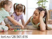 Happy family. Young mother playing ludo boardgame with her daughters while spending time together at home. Стоковое фото, фотограф Оксана Кузьмина / Фотобанк Лори
