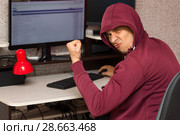 Интернет тролль у компьютера. Агрессивный молодой человек пишет вредные комментарии в сети и радуется. Стоковое фото, фотограф Лариса Капусткина / Фотобанк Лори