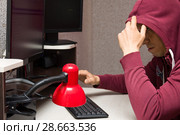 Интернет тролль у компьютера. Злобный мужчина в капюшоне общается в сети интернет. Стоковое фото, фотограф Лариса Капусткина / Фотобанк Лори