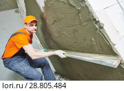 Plasterer smoothing fresh plaster on wall by straightedge trowel. Стоковое фото, фотограф Дмитрий Калиновский / Фотобанк Лори