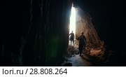Group of young explorers in helmets enters to the dark cave. Стоковое видео, видеограф Константин Шишкин / Фотобанк Лори
