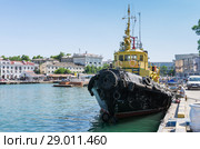 Sea tug at the pier. Russia, the peninsula of Crimea, the city of Sevastopol. 06/10/2018: Sea tugboat "Sevastopolets" at the pier in the Artillery Bay. View of the Kornilov embankment. Редакционное фото, фотограф Вадим Орлов / Фотобанк Лори