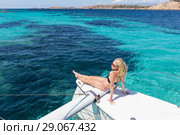 Woman relaxing on a summer sailing cruise, sitting on a luxury catamaran near picture perfect white sandy beach on Spargi island in Maddalena Archipelago, Sardinia, Italy. Стоковое фото, фотограф Matej Kastelic / Фотобанк Лори