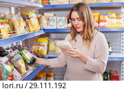 Woman customer choosing groats in grocery food shop. Стоковое фото, фотограф Яков Филимонов / Фотобанк Лори