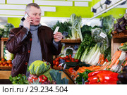man looking at shopping list, speaking by phone. Стоковое фото, фотограф Яков Филимонов / Фотобанк Лори