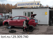 Мастер по шиномонтажу катит колесо (2018 год). Редакционное фото, фотограф Дмитрий Неумоин / Фотобанк Лори