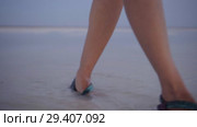 girl in green sandals splash through the puddles of salt lake at sunset time. Стоковое видео, видеограф Ирина Мойсеева / Фотобанк Лори