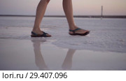 girl in green sandals splash through the puddles of salt lake at sunset time. Стоковое видео, видеограф Ирина Мойсеева / Фотобанк Лори