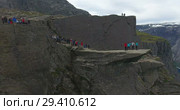 Группа людей фотографируется на Языке Тролля (Trolltunga). Природная достопримечательность в районе Одды (Odda). Норвегия (2018 год). Редакционное видео, видеограф Кекяляйнен Андрей / Фотобанк Лори