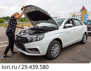 Девушка открывает капот нового автомобиля Лада Веста (2018 год). Редакционное фото, фотограф Вячеслав Палес / Фотобанк Лори