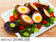 Tasty scotch eggs served with greens, leek and tomatoes at plate. Стоковое фото, фотограф Яков Филимонов / Фотобанк Лори