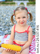 Little girl eating corn on the cob on the seaside. Стоковое фото, фотограф ivolodina / Фотобанк Лори