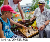 Дедушка и внук играют в шахматы на улице (2018 год). Редакционное фото, фотограф Вячеслав Палес / Фотобанк Лори