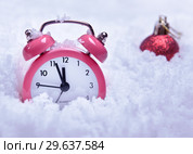 Круглые часы будильник в снегу рядом с новогодним красным шаром. Стоковое фото, фотограф Элина Гаревская / Фотобанк Лори