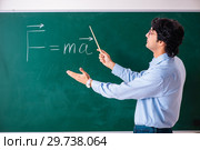 Young male physic standing in front of the green board. Стоковое фото, фотограф Elnur / Фотобанк Лори