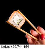 Японская кухня. Суши ролл. Фото для меню азиатская кухня. Роллы с лососем держит в руке на палочках девушка с красными ноглями. Стоковое фото, фотограф Евгений Бобков / Фотобанк Лори