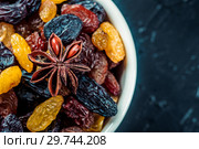 White ceramic bowl with Assortment of Raisins, yellow, blue, black, golden raisin and anise on black background. Healthy snack. Vega Food. Food mix background, top view, copy space, banner. Стоковое фото, фотограф Евгений Бобков / Фотобанк Лори