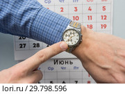 Рука офисного специалиста указывает на наручные часы, на заднем плане настенный календарь. Стоковое фото, фотограф Иванов Алексей / Фотобанк Лори
