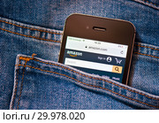 Сайт Amazon.com на экране телефона. Смартфон лежит в заднем кармане джинсовых штанов (2019 год). Редакционное фото, фотограф E. O. / Фотобанк Лори