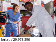 thoughtful afro paramedical using defibrillator for providing medical care to patient. Стоковое фото, фотограф Яков Филимонов / Фотобанк Лори