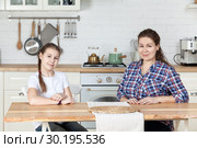 Мама и десятилетняя дочь сидят за столом на кухне. Стоковое фото, фотограф Кекяляйнен Андрей / Фотобанк Лори