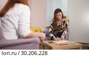 A session at the psychologist. The doctor gives a paper to a smiling patient and the patient starts drawing. Стоковое видео, видеограф Константин Шишкин / Фотобанк Лори