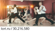Adult pairs dancing tango movements in modern dance studio. Стоковое фото, фотограф Яков Филимонов / Фотобанк Лори