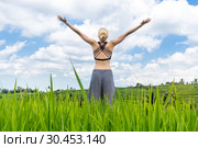 Relaxed casual sporty woman, arms rised to the sky, enjoying pure nature at beautiful green rice fields on Bali. Стоковое фото, фотограф Matej Kastelic / Фотобанк Лори