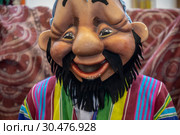 Артист в маске позитивного дехканина на фестивале "Навруз-2019" в павильоне ВДНХ на стенде  Узбекистана в городе Москве, Россия. Редакционное фото, фотограф Николай Винокуров / Фотобанк Лори