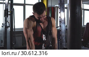 Motivated man standing near machine and pulling down handle while exercising arms. Стоковое видео, видеограф Виктор Аллин / Фотобанк Лори