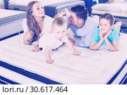 Small client with his happy family choosing right mattress in home furnishings store. Стоковое фото, фотограф Яков Филимонов / Фотобанк Лори