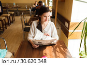 The girl reads the newspaper in Baranochka Candies cafe. a look in a fullface (2019 год). Редакционное фото, фотограф Владимир Арсентьев / Фотобанк Лори