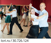 Positive adult couples dancing tango together in modern studio. Стоковое фото, фотограф Яков Филимонов / Фотобанк Лори