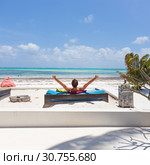 Relaxed man in luxury lounger, arms rised, enjoying summer vacations on beautiful beach. Стоковое фото, фотограф Matej Kastelic / Фотобанк Лори