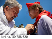 Российский политик Павел Грудинин повязывает октябрятам пионерские галстуки на всероссийской торжественной линейке, посвященной Дню пионерии и приему в пионеры на Красной площади города Москвы, Россия (2019 год). Редакционное фото, фотограф Николай Винокуров / Фотобанк Лори