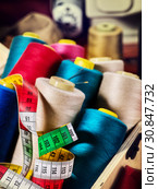 Coil threads for overlock and measuring tape on serger background. Стоковое фото, фотограф Gennadiy Poznyakov / Фотобанк Лори