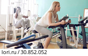 Group of people exercising with weight and on simulators in gym. Стоковое видео, видеограф Яков Филимонов / Фотобанк Лори