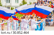 Russia Samara May 2019: Beautifully dressed schoolchildren waving the Russian flag at an open city festival. The last school bell . Редакционное фото, фотограф Акиньшин Владимир / Фотобанк Лори
