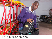 Driver of pedicab inspecting luggage basket. Стоковое фото, фотограф Яков Филимонов / Фотобанк Лори