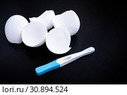 Infertility. Negative pregnancy test and eggshell on black. Стоковое фото, фотограф Papoyan Irina / Фотобанк Лори