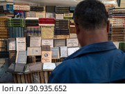 Мужчина смотрит на старые книги в букинистической лавке на Арбате в городе Москве, Россия (2019 год). Редакционное фото, фотограф Николай Винокуров / Фотобанк Лори