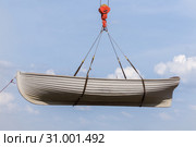 Rowing boat hanging on a crane hook on a blue sky background. Стоковое фото, фотограф Олег Белов / Фотобанк Лори