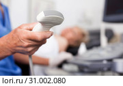 Male doctor holding ultrasonic probe in hand, ultrasound machine and patient ready for diagnostic. Стоковое фото, фотограф Яков Филимонов / Фотобанк Лори